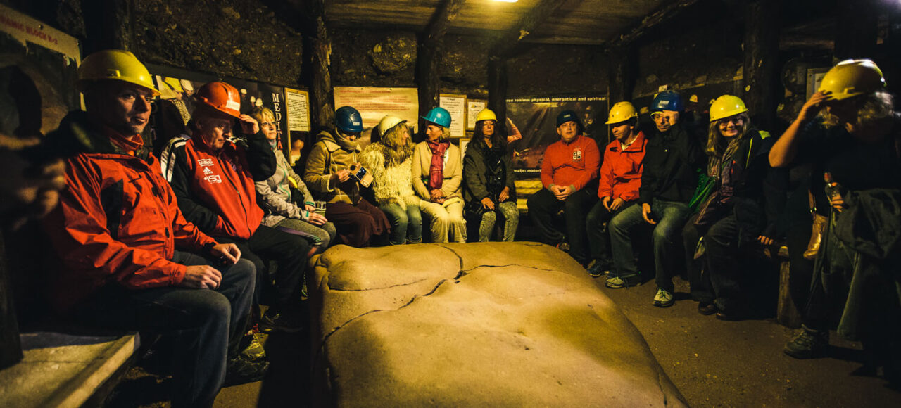 Visitors seated around the Megalith K-2 stone inside the Ravne Tunnels near the Bosnian Pyramid complex.