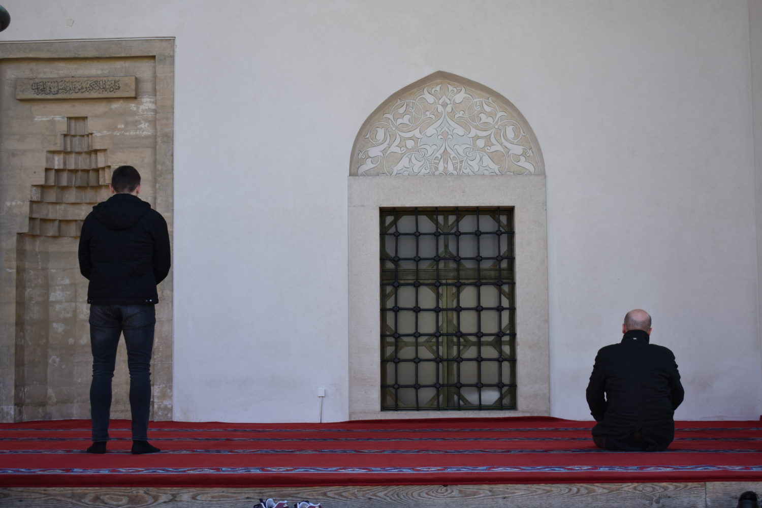 Two men performing prayer in the courtyard of Gazi Husrev-beg Mosque in Sarajevo