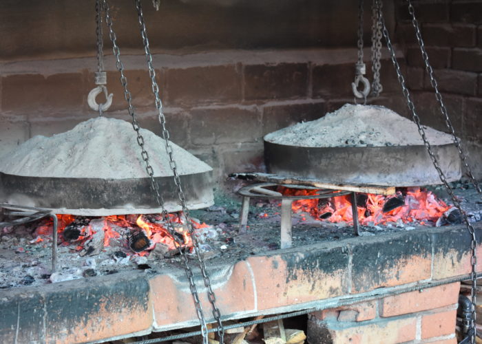 Traditional Bosnian cooking method 'Ispod Sača' with meat and vegetables being prepared under a metal lid covered with hot coals