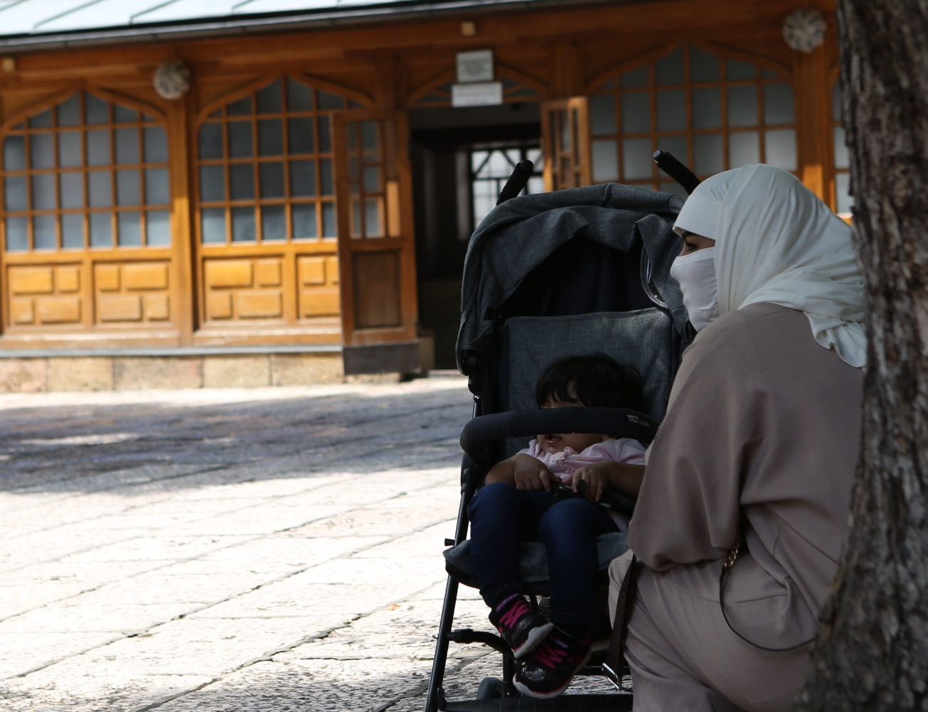 A woman and child in a stroller in the courtyard of Gazi Husrev-beg Mosque in Sarajevo