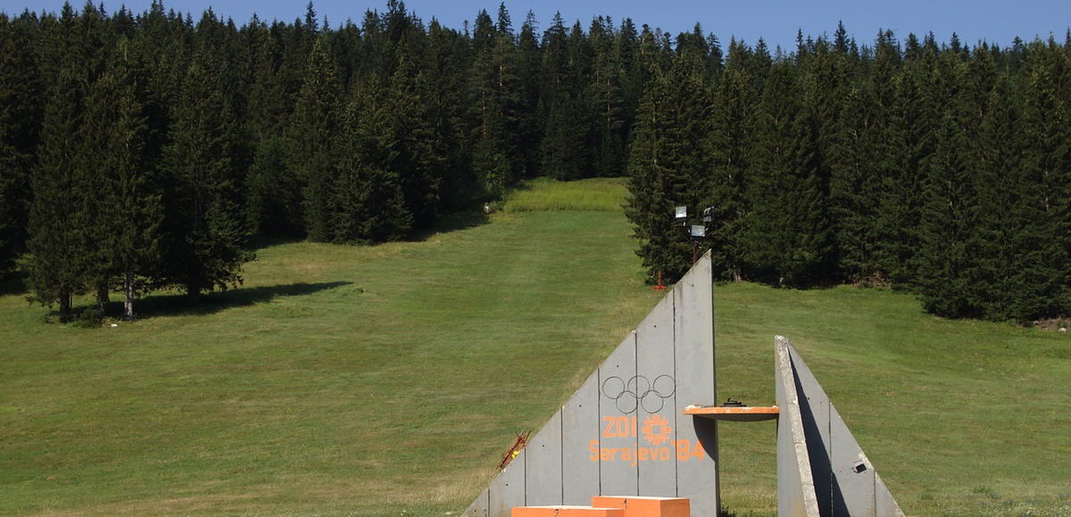Concrete Olympic monument surrounded by green forest on Igman Mountain.