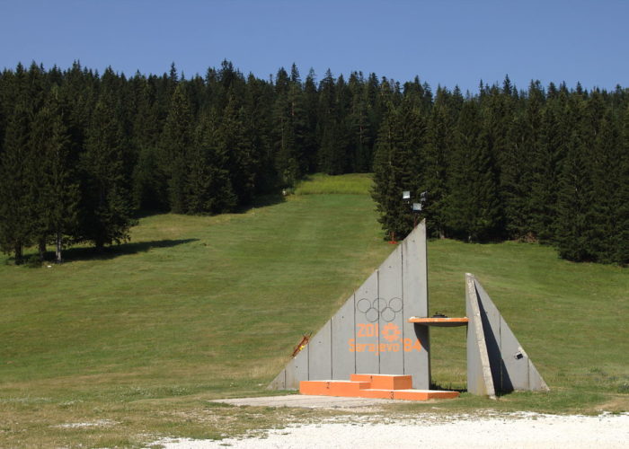 Concrete Olympic monument surrounded by green forest on Igman Mountain.