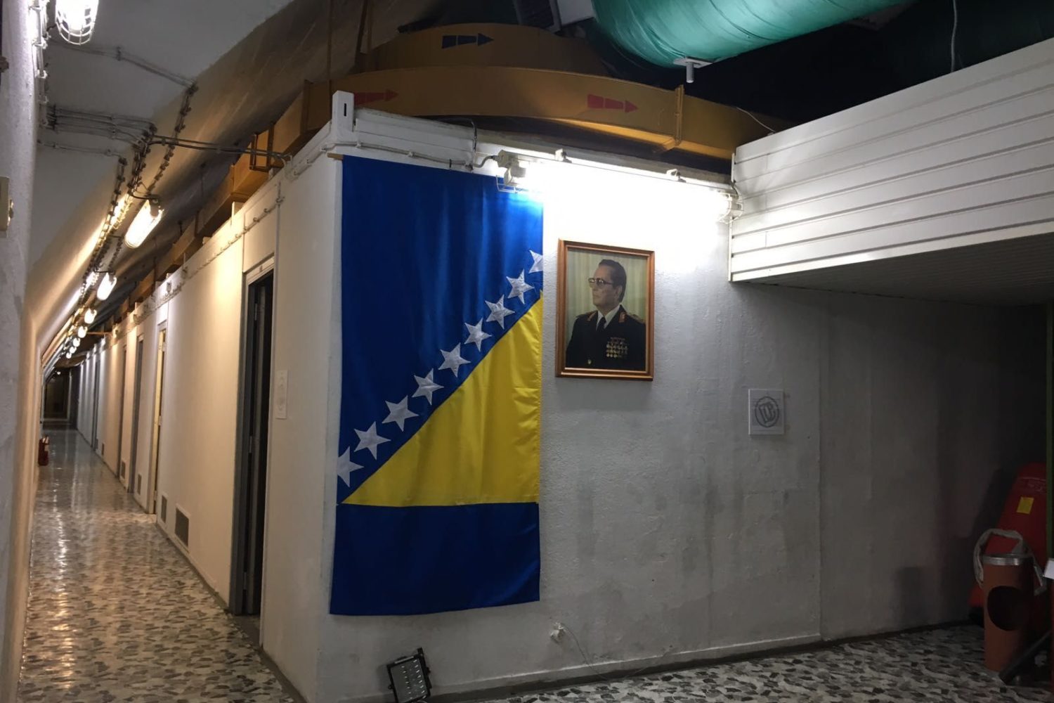 Hallway inside Tito's bunker in Bosnia, featuring a Bosnian flag and a portrait of Tito during a Sarajevo Insider tour
