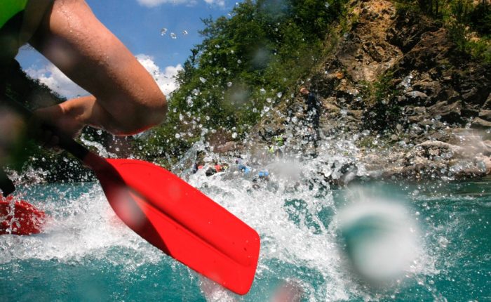 Close-up view of an oar splashing water during a white-water rafting adventure on the Neretva River.