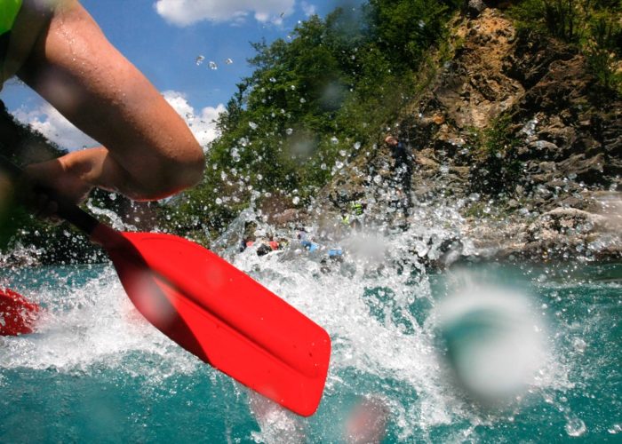 Close-up view of an oar splashing water during a white-water rafting adventure on the Neretva River.