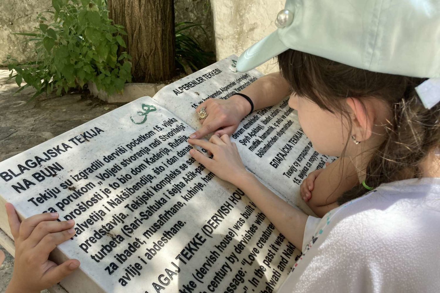 Children reading a signboard at Blagaj Tekke, a historic Dervish monastery in Bosnia and Herzegovina.